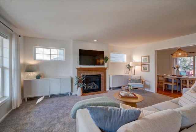 living room with a tiled fireplace, plenty of natural light, baseboards, and carpet floors