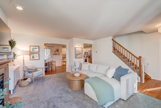 living room with stairs, light wood-style floors, and a tile fireplace