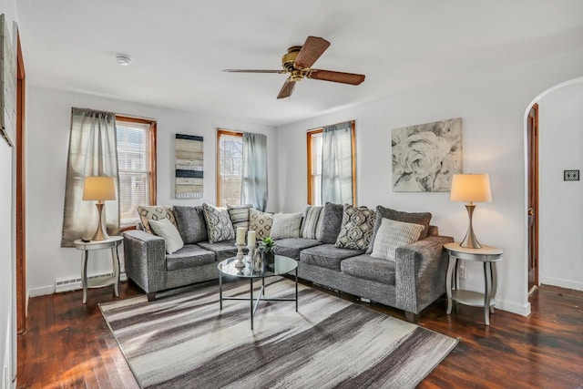 living room featuring arched walkways, baseboard heating, ceiling fan, wood finished floors, and baseboards