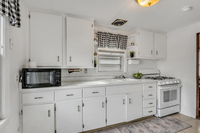 kitchen featuring black microwave, white gas stove, a sink, and white cabinets