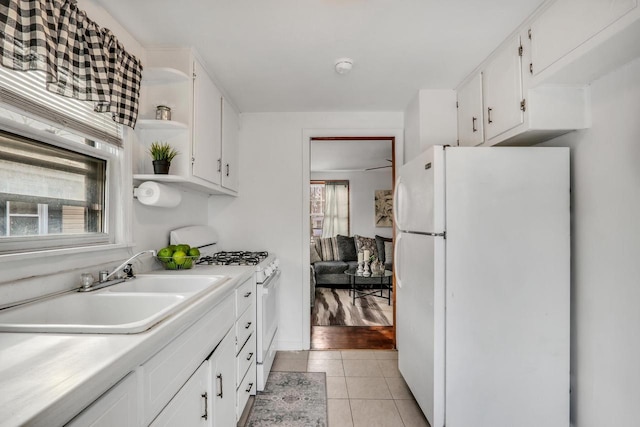 kitchen featuring light tile patterned floors, light countertops, white cabinetry, a sink, and white appliances