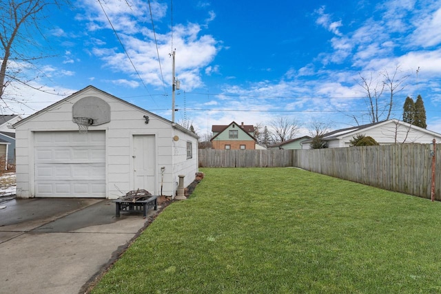 view of yard featuring an outbuilding, driveway, a detached garage, and fence