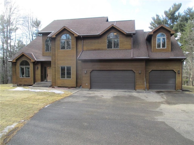 view of front of property with aphalt driveway, a front yard, and an attached garage