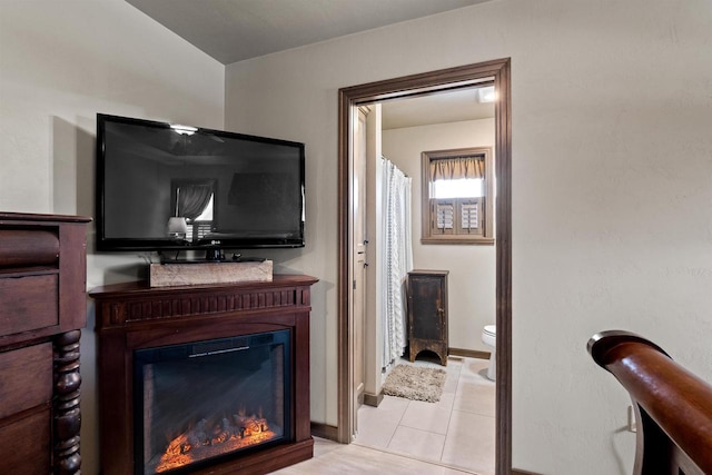 tiled living room with a glass covered fireplace and baseboards