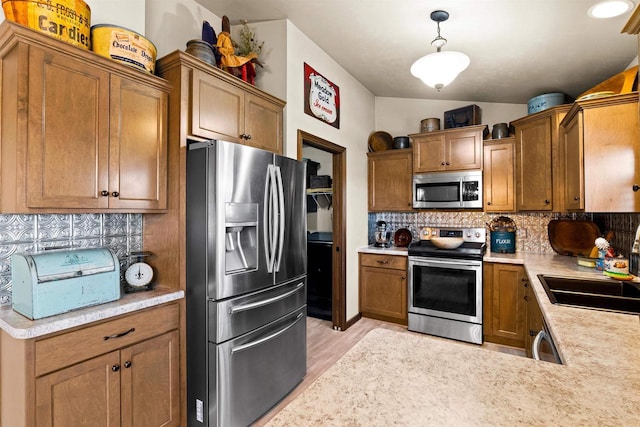 kitchen with pendant lighting, brown cabinets, light countertops, decorative backsplash, and appliances with stainless steel finishes