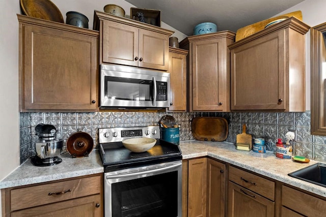 kitchen featuring light countertops, appliances with stainless steel finishes, and decorative backsplash