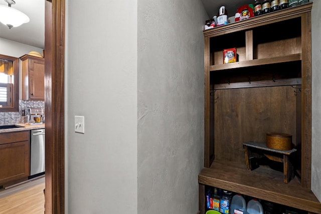 mudroom featuring light wood-style floors, a textured wall, and a sink