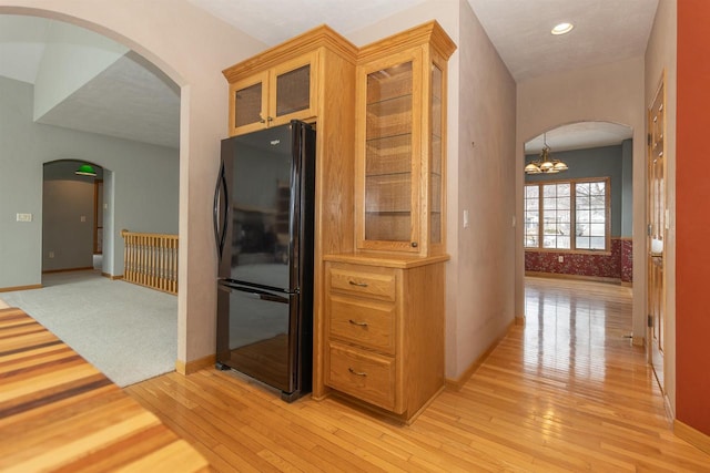 kitchen with arched walkways, freestanding refrigerator, and light wood-style flooring