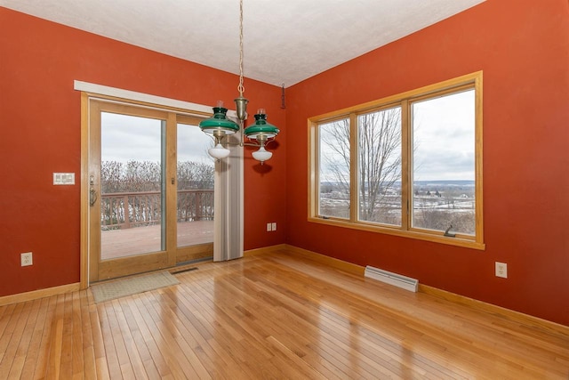 unfurnished dining area featuring visible vents, baseboards, hardwood / wood-style flooring, and a healthy amount of sunlight