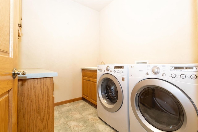 clothes washing area with washer and clothes dryer, cabinet space, and baseboards