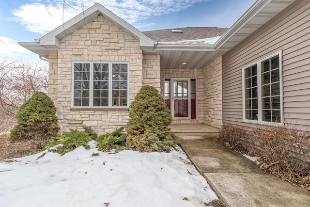 view of exterior entry with a shingled roof and stone siding