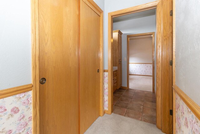 hallway with carpet floors and tile patterned flooring