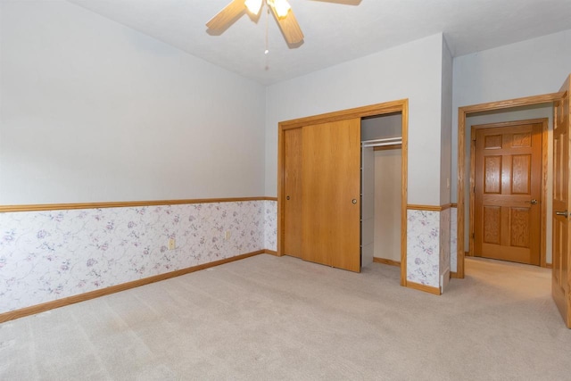 unfurnished bedroom featuring light carpet, a closet, baseboards, and wallpapered walls