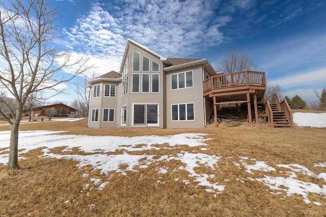 snow covered house featuring stairway and a wooden deck