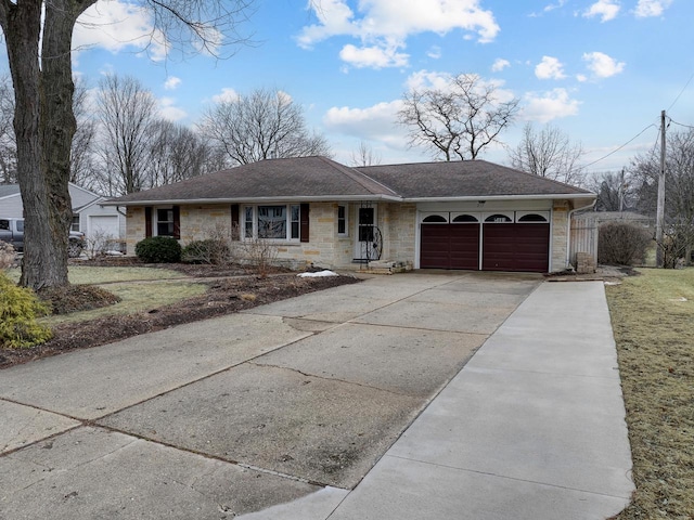 ranch-style home with a garage, stone siding, roof with shingles, and concrete driveway