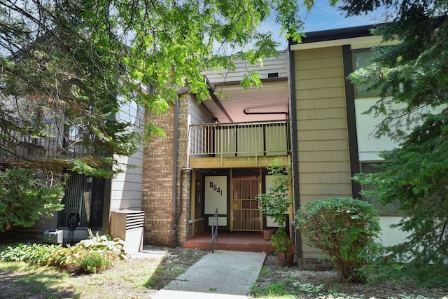 view of front of home featuring brick siding and a balcony