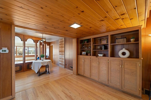 interior space featuring light wood-style floors, wood ceiling, wooden walls, and visible vents