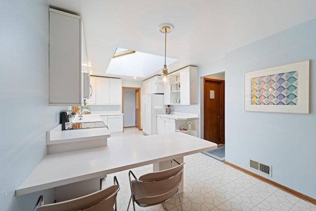 kitchen featuring a peninsula, white appliances, visible vents, white cabinets, and light countertops