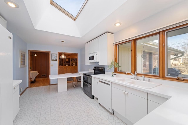 kitchen with a skylight, light countertops, white cabinets, a sink, and white appliances