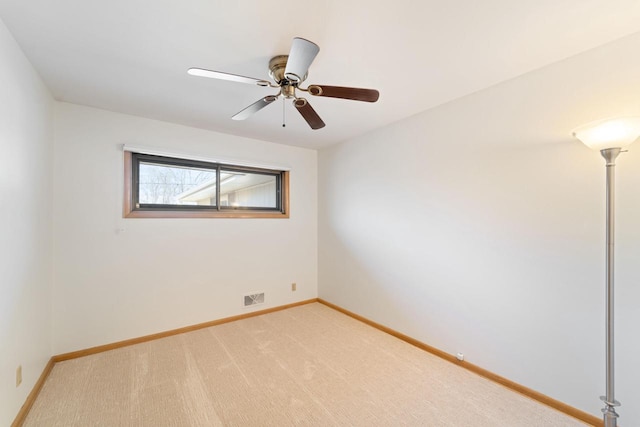 empty room featuring light carpet, ceiling fan, visible vents, and baseboards