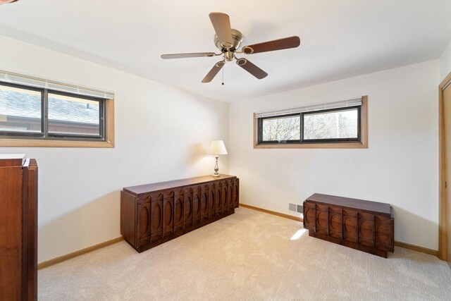 interior space featuring baseboards, visible vents, ceiling fan, and carpet flooring