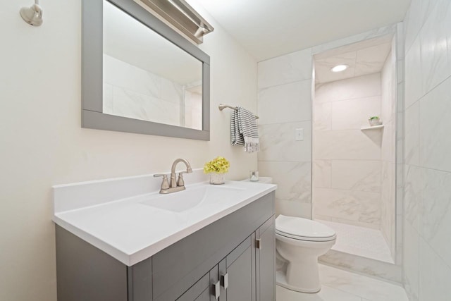 bathroom with a tile shower, marble finish floor, vanity, and toilet