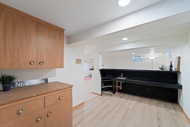 kitchen with baseboards, light wood-style flooring, and brown cabinets