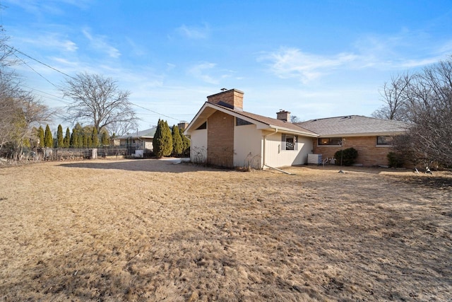 rear view of house with a chimney and fence