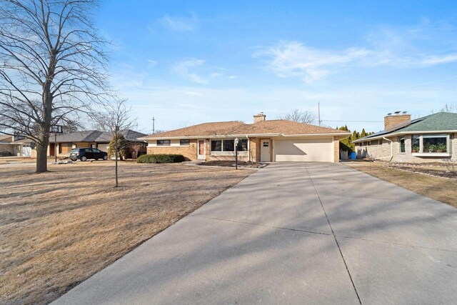 ranch-style home featuring a garage, driveway, a chimney, and brick siding