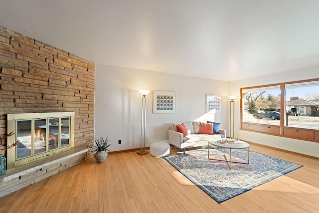 living area featuring a fireplace, baseboards, and wood finished floors