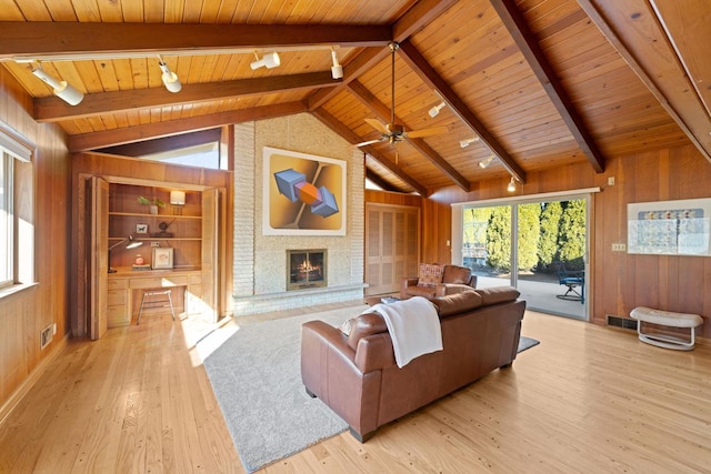 living area featuring vaulted ceiling with beams, light wood finished floors, wood ceiling, and wooden walls