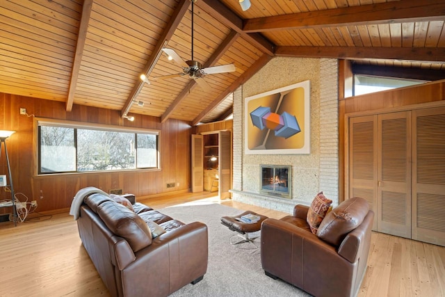 living room featuring wooden walls, a glass covered fireplace, wooden ceiling, wood finished floors, and vaulted ceiling with beams