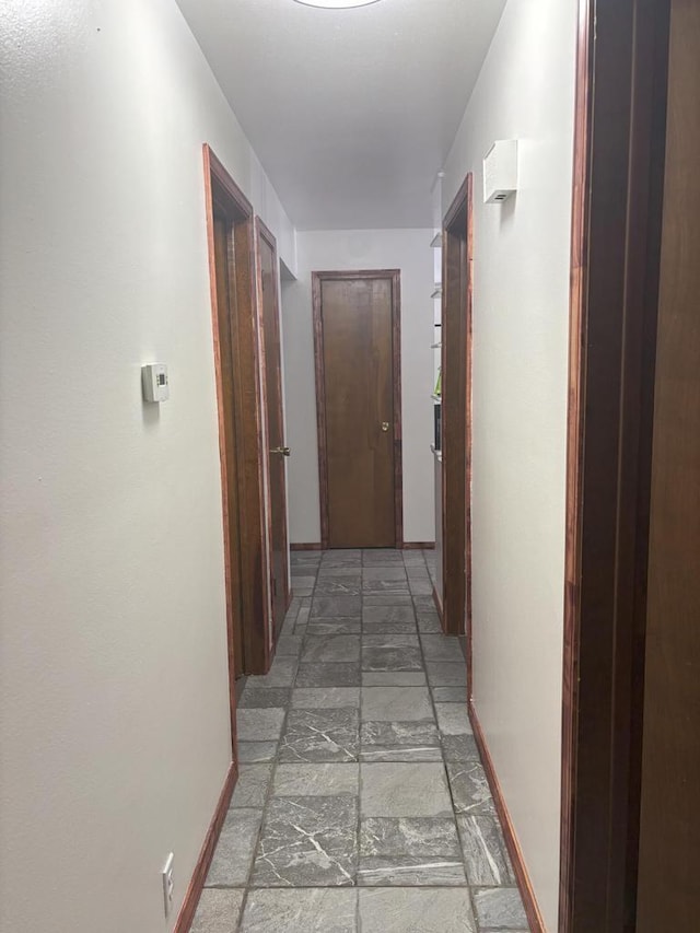 corridor with baseboards and stone finish floor