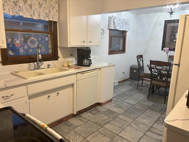 kitchen with stone tile flooring, light countertops, white cabinetry, a sink, and white appliances