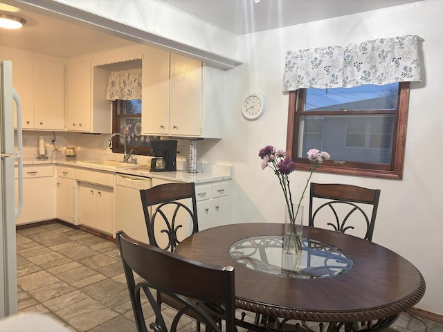 kitchen with stone tile floors, white appliances, a sink, white cabinetry, and light countertops