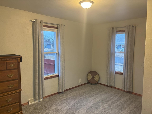 carpeted spare room featuring visible vents and baseboards