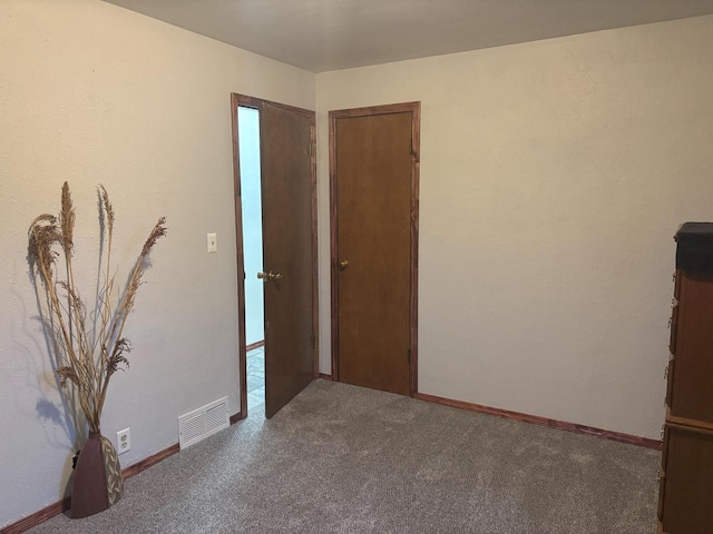 unfurnished room with carpet, visible vents, and baseboards