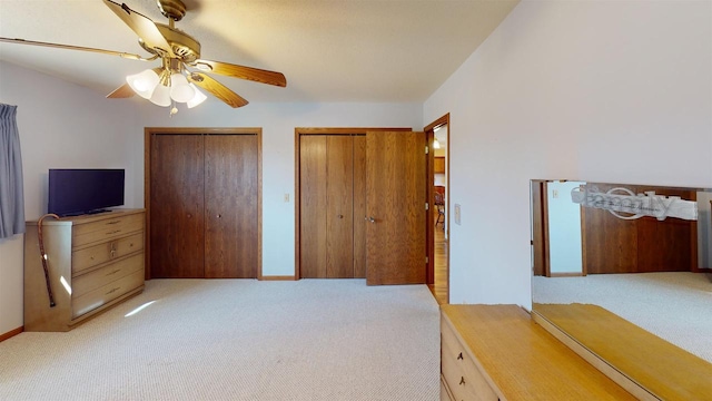 carpeted bedroom featuring multiple closets and ceiling fan