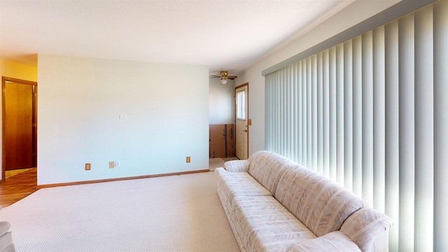 living room featuring ceiling fan, baseboards, and light colored carpet