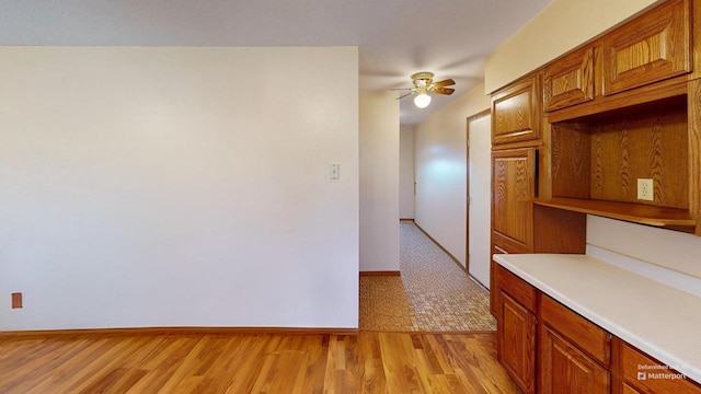 kitchen with a ceiling fan, light countertops, open shelves, light wood finished floors, and brown cabinetry