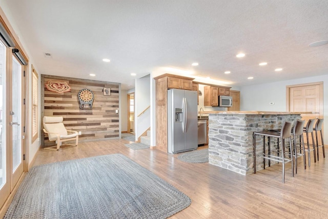 N8111 Castaway Dr, New Lisbon, WI 53950 - kitchen with a breakfast bar area, light wood-style flooring, wooden walls, an accent wall, and stainless steel appliances