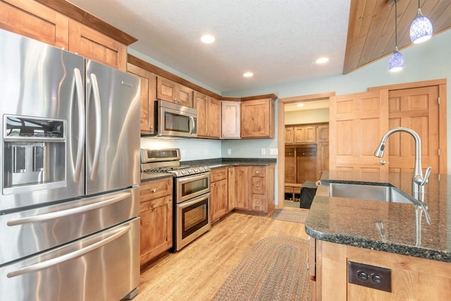 N8111 Castaway Dr, New Lisbon, WI 53950 - kitchen featuring light wood finished floors, dark stone counters, appliances with stainless steel finishes, decorative light fixtures, and a sink