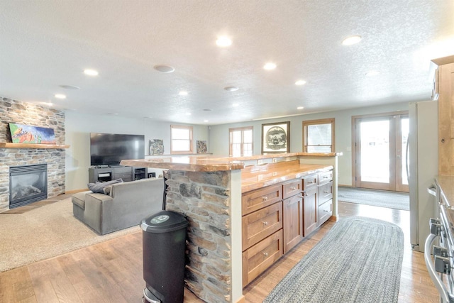 N8111 Castaway Dr, New Lisbon, WI 53950 - kitchen featuring a fireplace, light wood-style floors, open floor plan, a textured ceiling, and light stone countertops