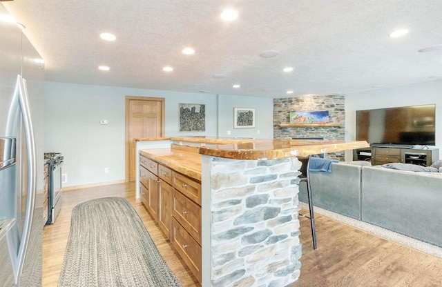 N8111 Castaway Dr, New Lisbon, WI 53950 - kitchen featuring a textured ceiling, recessed lighting, a kitchen breakfast bar, appliances with stainless steel finishes, and light wood finished floors