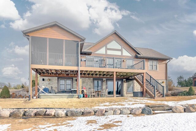 N8111 Castaway Dr, New Lisbon, WI 53950 - snow covered back of property with stairs, stone siding, a deck, and a sunroom