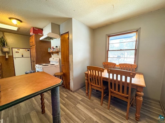 dining area featuring light wood-type flooring and a textured ceiling