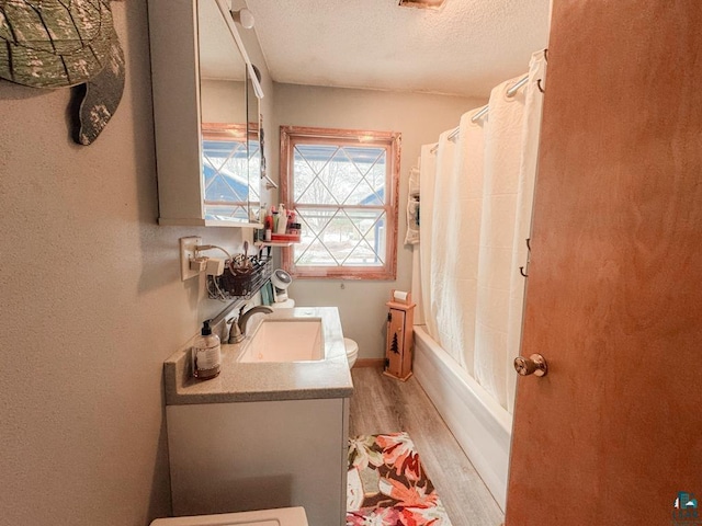 bathroom featuring a textured ceiling, wood finished floors, vanity, baseboards, and shower / tub combo with curtain