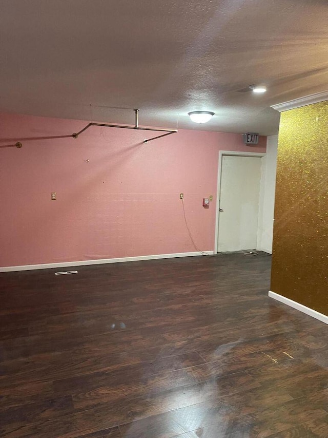 unfurnished room featuring a textured ceiling, baseboards, and wood finished floors