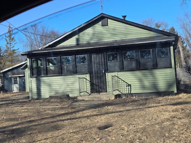 view of front of home with entry steps and a sunroom