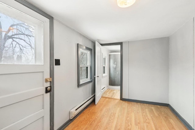 entryway featuring light wood-type flooring, baseboard heating, and a baseboard radiator